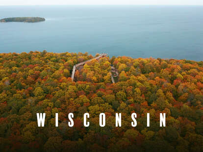 An eagle's eye view of a scenic overlook carving through fall foliage to a lake.