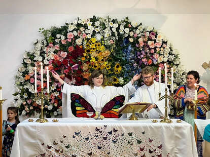 An Episcopalian leads a church service in front of a rainbow of flowers