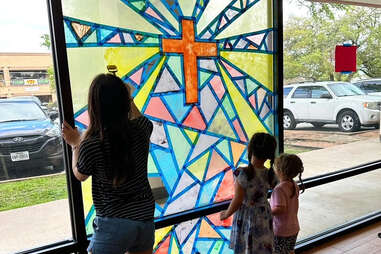 kids in front of a stained-glass window with a rainbow cross in austin, texas