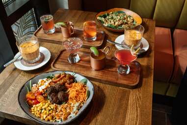 a spread of dishes and cocktails on a wood table at immigrant food in washington d.c.