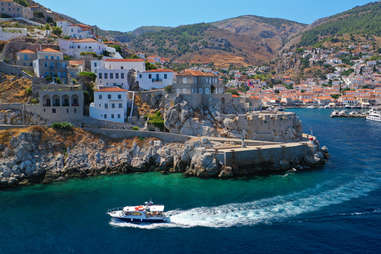 boat riding alongside the coast of hydra