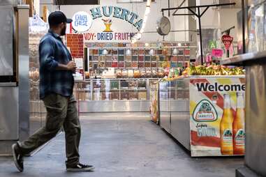 A customer walks past the colorful signage and foods in Grand Central Market.
