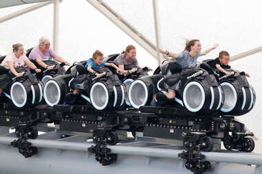 a family rides the new tron light cycle ride at disneyworld in orlando, florida